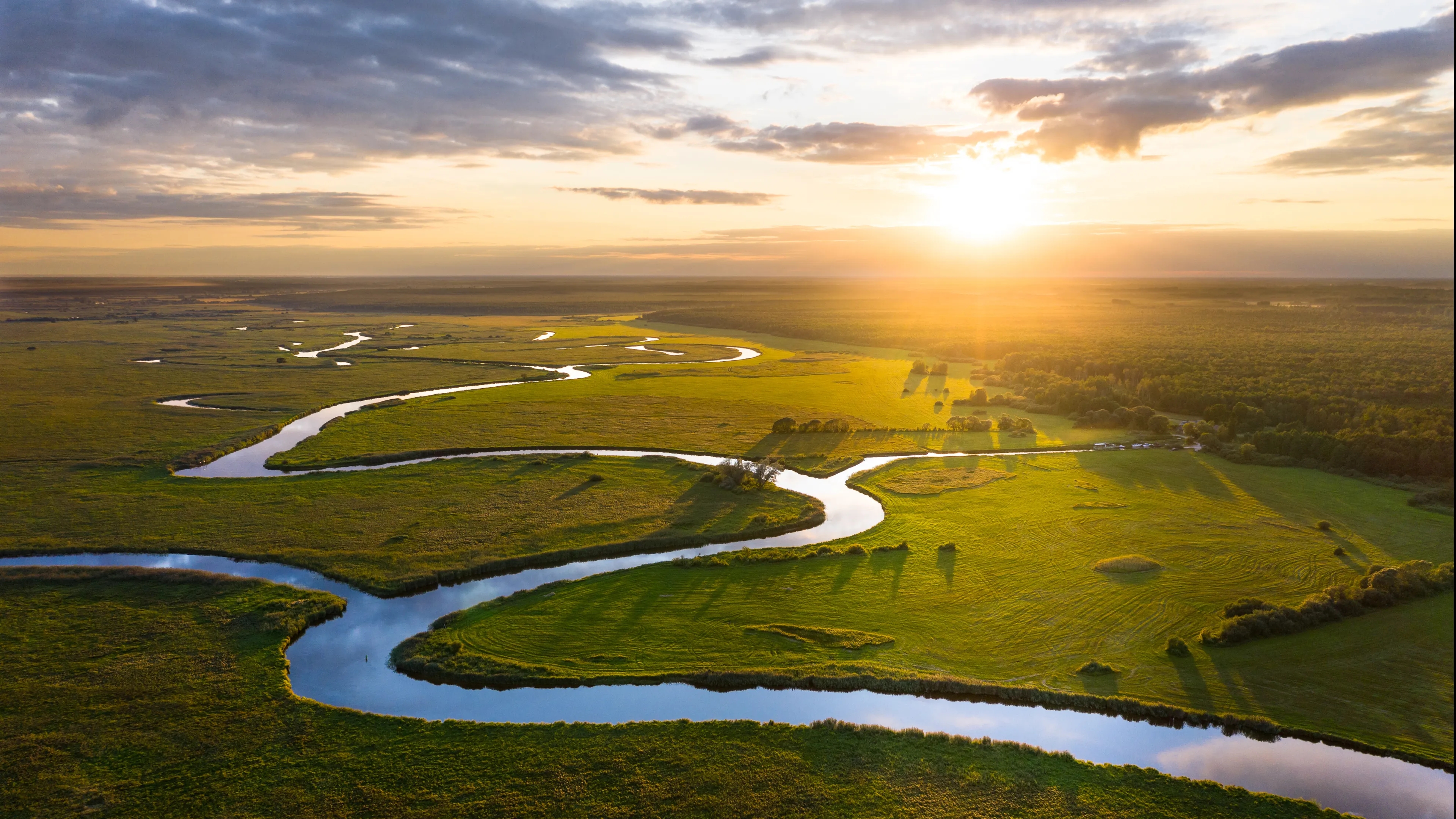 Fluss- und Grünlandschaft im Sonnenuntergang