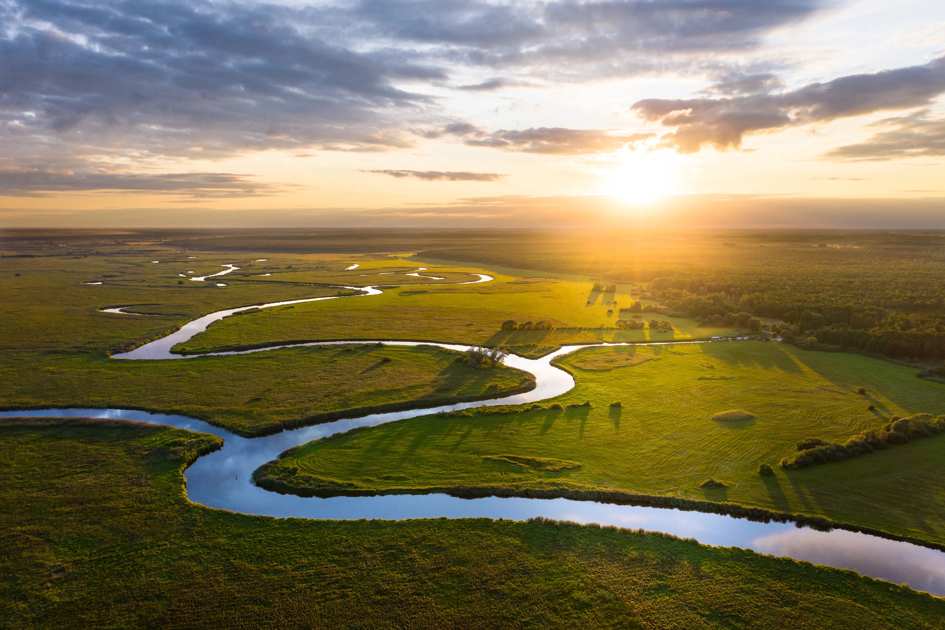 Fluss- und Grünlandschaft im Sonnenuntergang